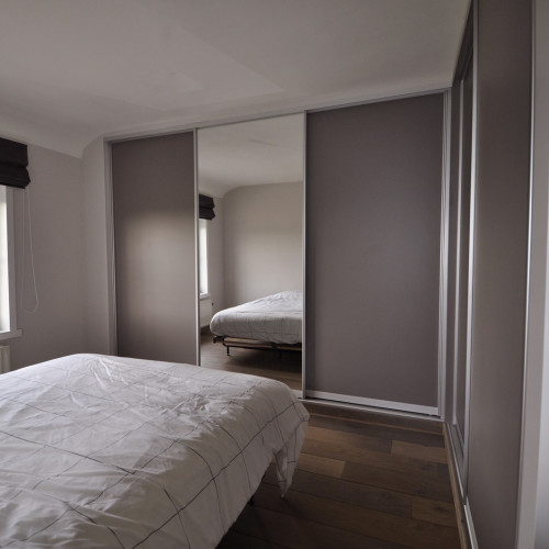 In deze slaapkamer werd een spiegel voorzien in de schuifdeuren. Een spiegel in een schuifdeur geeft altijd een verruimend effect én je hoeft geen aparte spiegel meer te hebben bij het passen van
